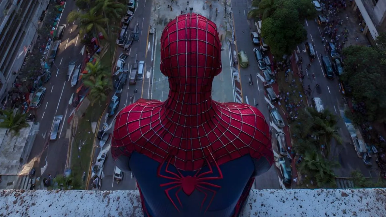 Desktop wallpaper: a Spider-Man figure seen from behind on a ledge above a busy city avenue