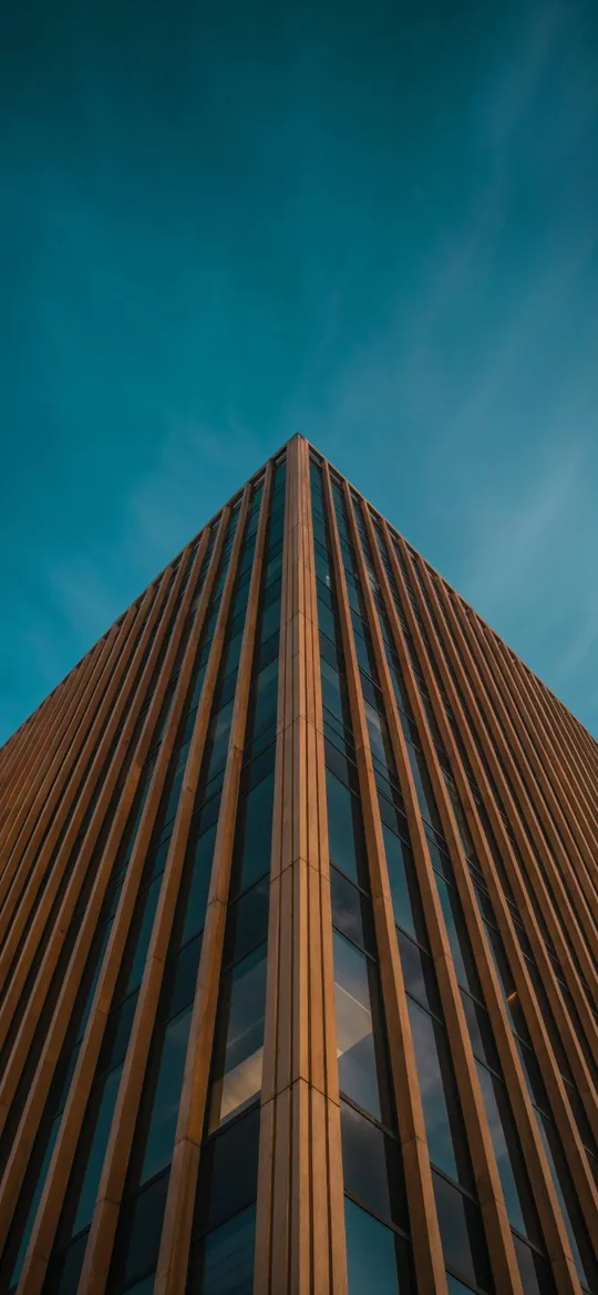 Phone wallpaper: a wood-slatted glass tower seen from below against a teal sky